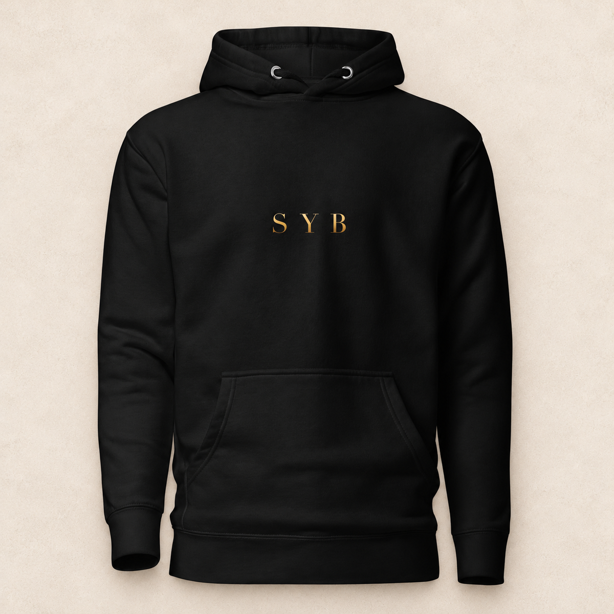 wordmark hoodie in black with original SYB gold artwork on a pale limestone studio background
