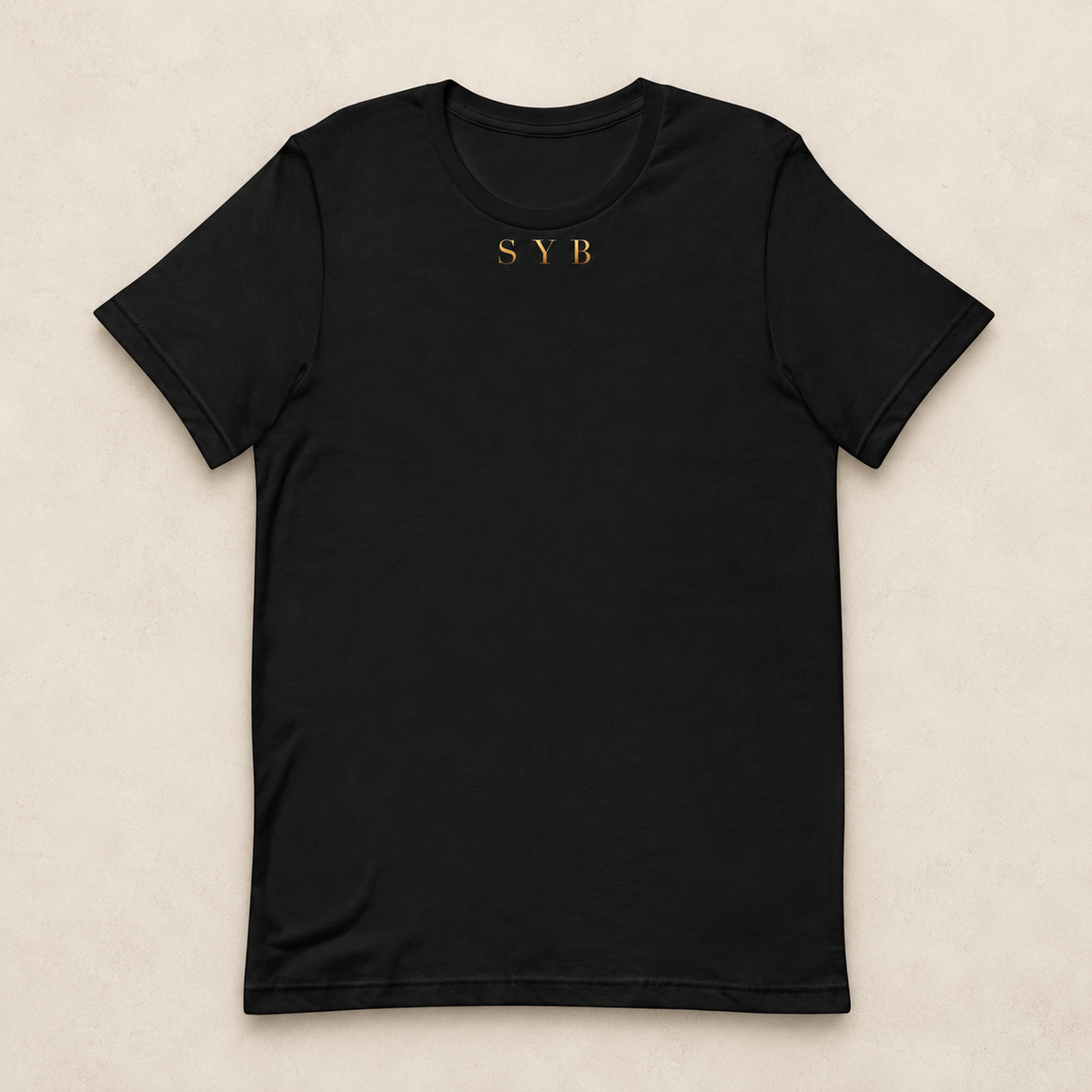 Wordmark Tee in black with a small gold-tone SYB front print; studio mockup.